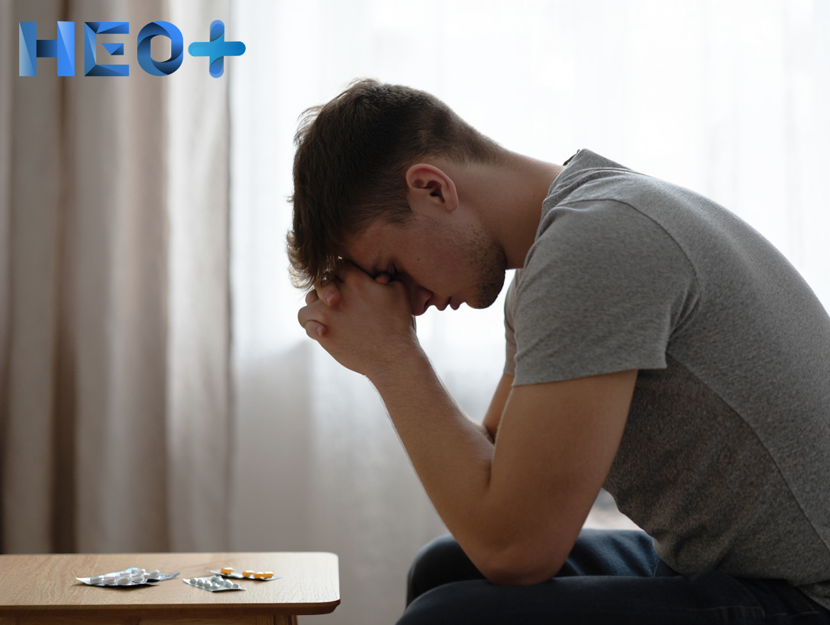 Молодой мужчина сидит за столом на котором таблетки экстази